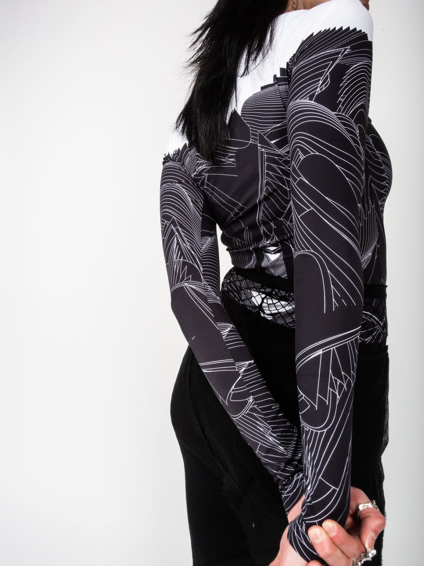 Close-up of side back view of male model wearing VinöniV / VinoniV Obsidian Feather Daydream jersey top bodysuit jersey top with soft feather-inspired black and white design.