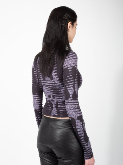 Back view of female model wearing VinöniV / VinoniV Noise fitted printed bodysuit jersey top in semi-purple color