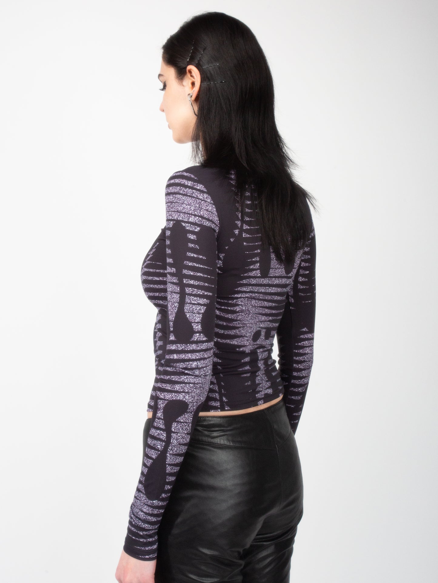 Side back view of female model wearing VinöniV / VinoniV Noise fitted printed bodysuit jersey top in semi-purple color
