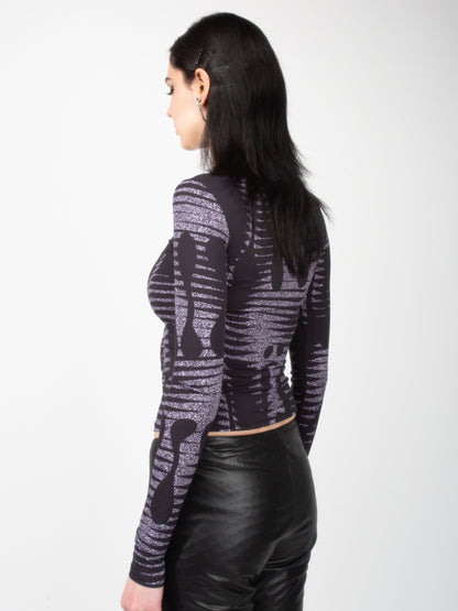 Side back view of female model wearing VinöniV / VinoniV Noise fitted printed bodysuit jersey top in semi-purple color