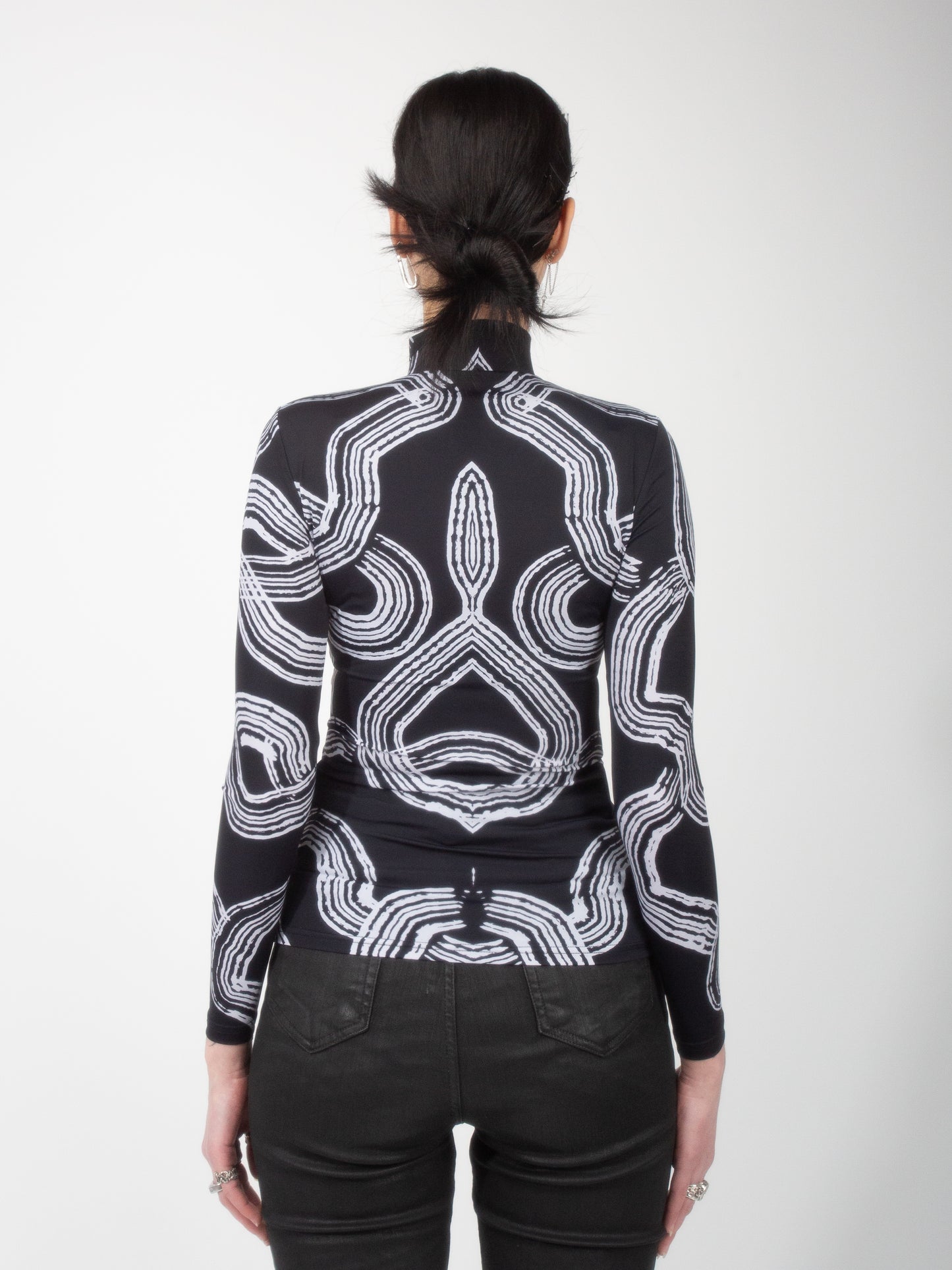 Back view of female model wearing Onyx Tide bodysuit jersey top black and white ocean print on jersey fabric by VinöniV / VinoniV featuring fluid, water-inspired design.