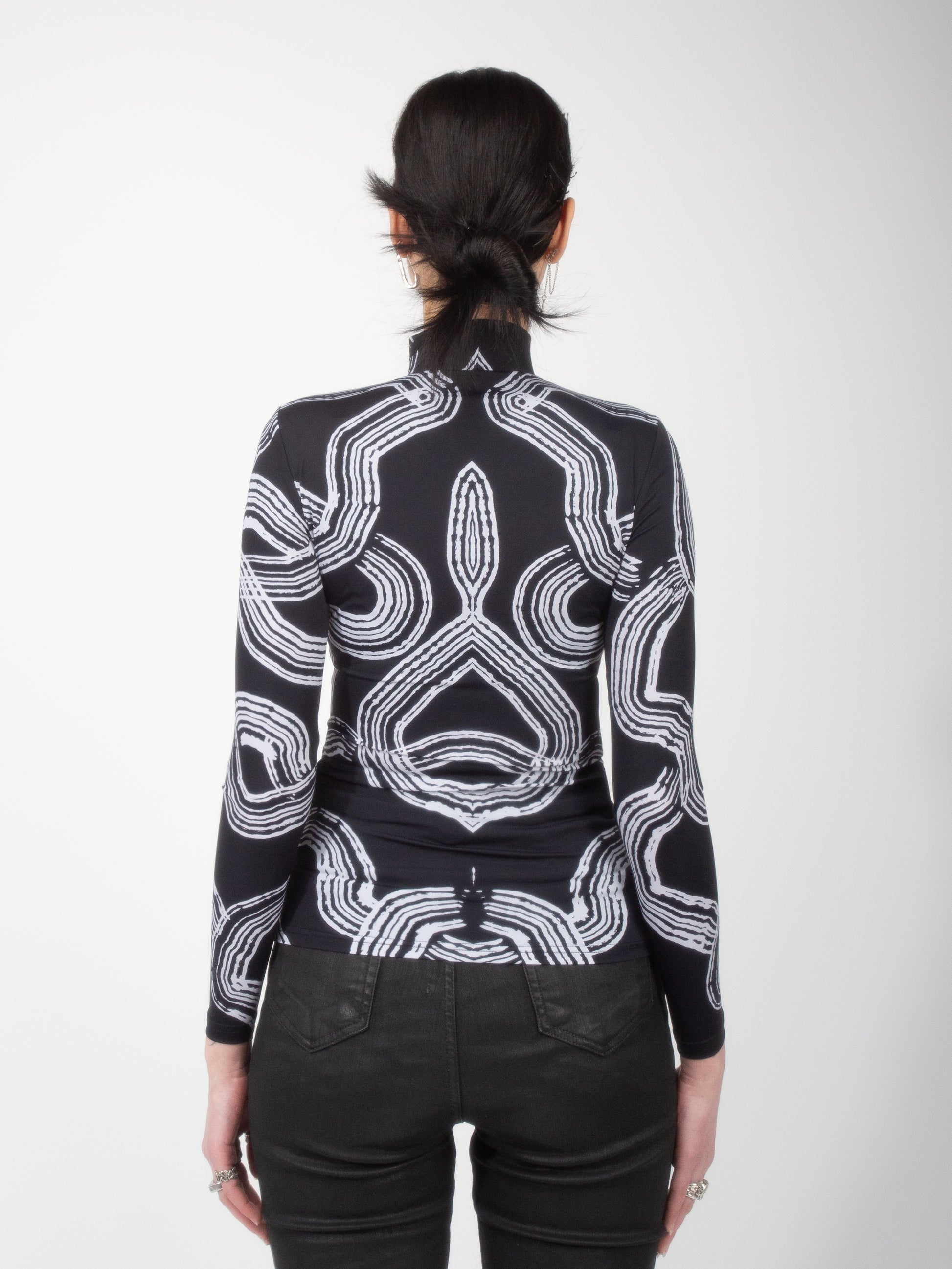 Back view of female model wearing Onyx Tide bodysuit jersey top black and white ocean print on jersey fabric by VinöniV / VinoniV featuring fluid, water-inspired design.