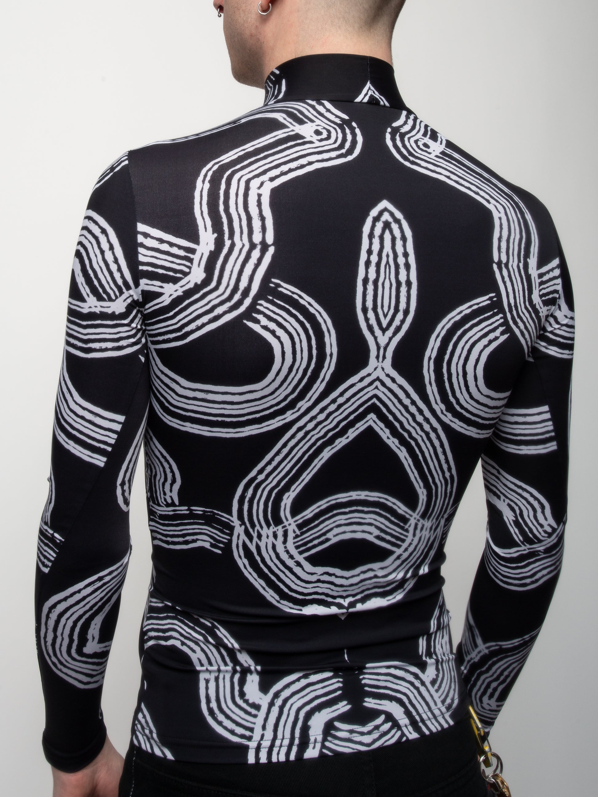 Close-up of male model wearing Onyx Tide bodysuit jersey top black and white ocean print on jersey fabric by VinöniV / VinoniV